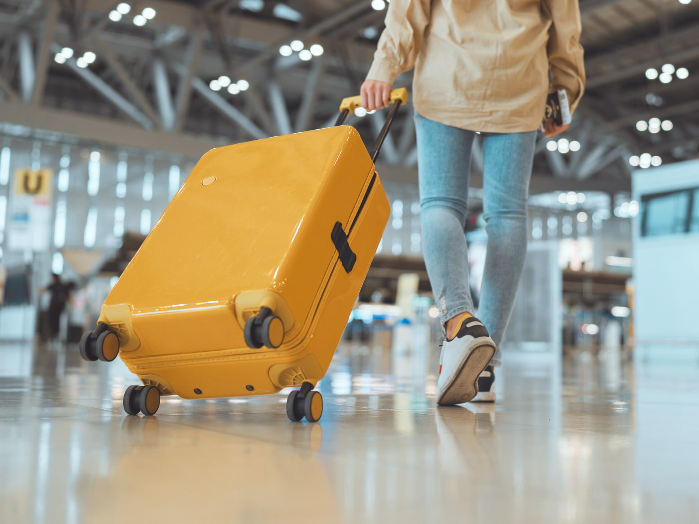 Passeggera con valigia nel moderno terminal dell’aeroporto.