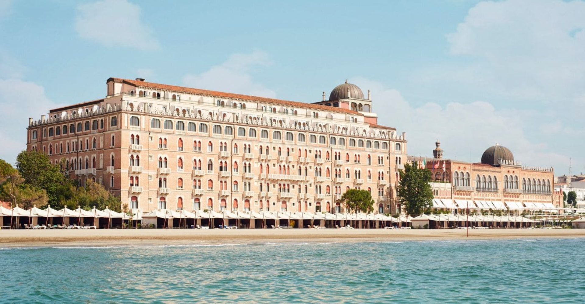 Il monumentale edificio dell'Hotel Excelsior Venice Lido con la prima fila di cabanas sulla spiaggia