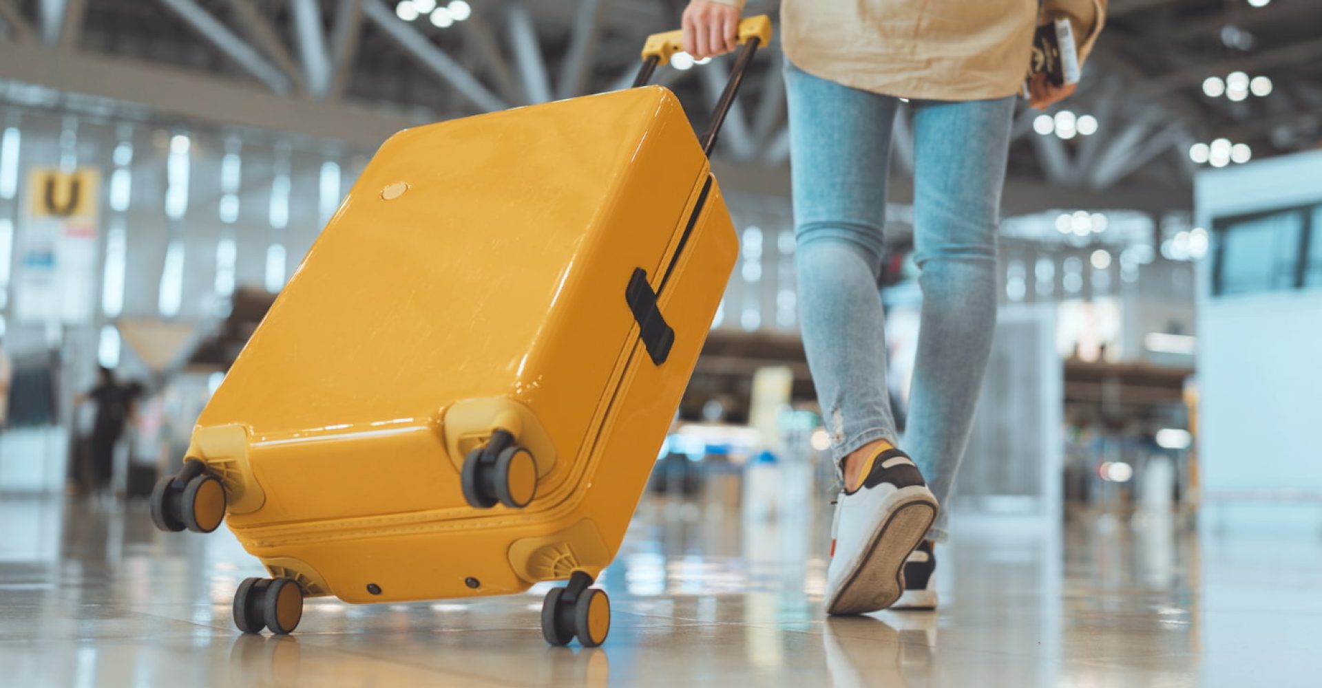 Passeggera con valigia nel moderno terminal dell’aeroporto.